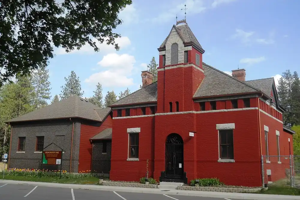Historic red brick Old Kootenai County Jail with a bell tower and tulips in Rathdrum, Idaho